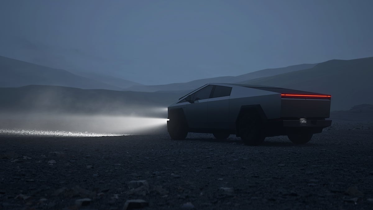 Tesla Cybertruck driving at night through a foggy landscape with headlights and rear light bar illuminated.