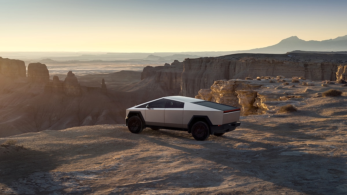 Tesla Cybertruck electric pickup parked on desert cliff at sunset showcasing futuristic design and off-road capability
