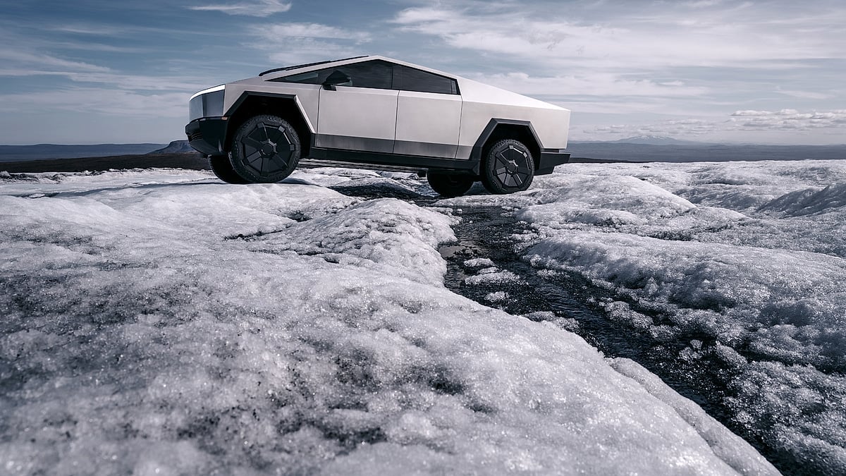 Tesla Cybertruck parked on an icy landscape under a dramatic sky, shown from the side profile.