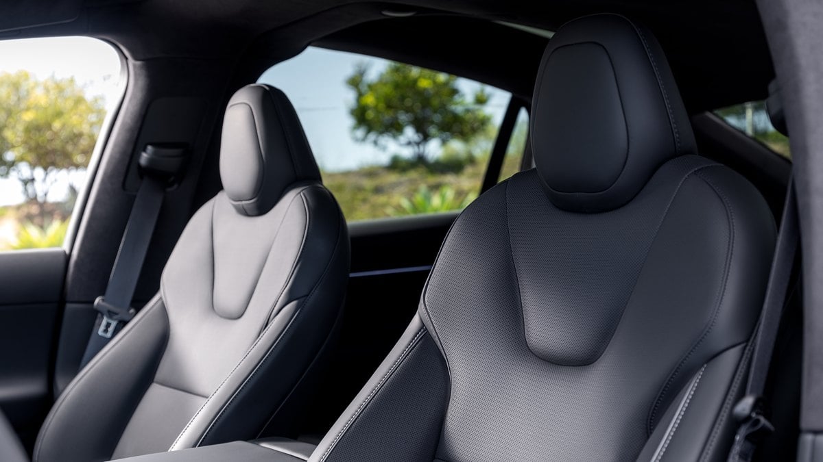 White Tesla Model X parked outdoors with falcon wing doors open showcasing electric SUV design