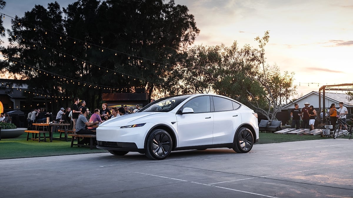 Tesla Model Y parked outdoors at a social gathering with people dining and string lights