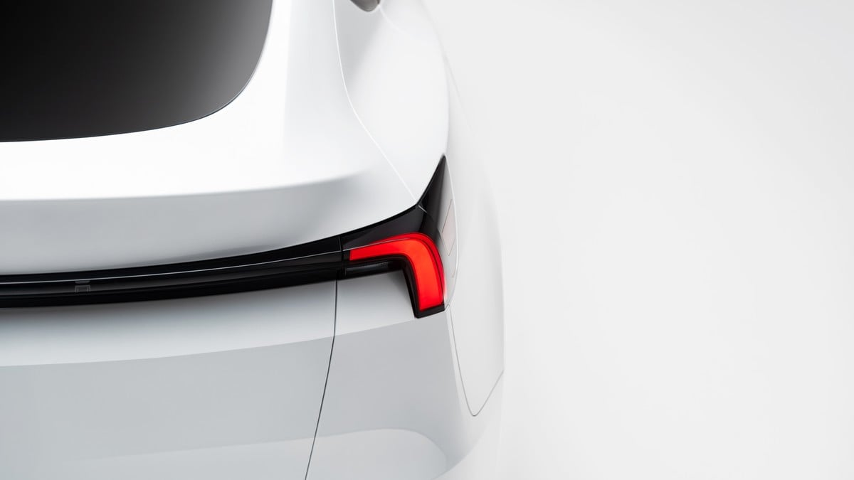 Rear view detail of white Tesla Model Y showing LED taillight design and smooth hatchback styling