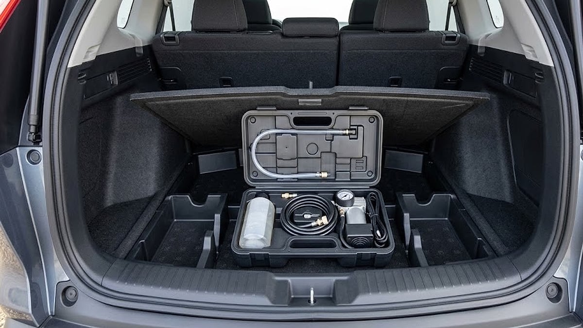 The 2026 Honda CR-V Hybrid's factory tire repair kit, complete with sealant and compressor, is stored organized under the rear load floor