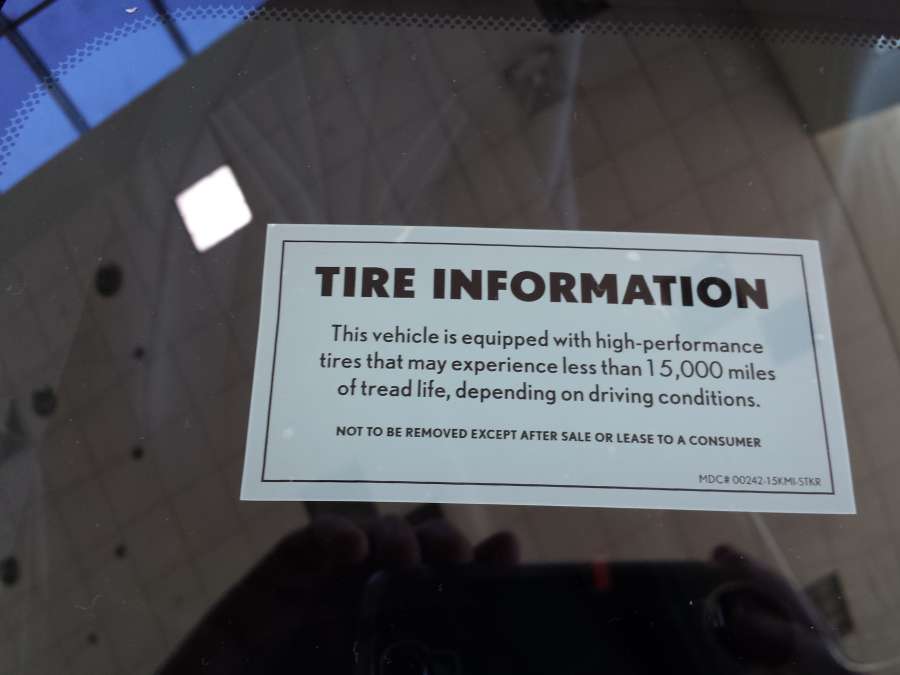 A window sticker warns of short tire life on a performance car