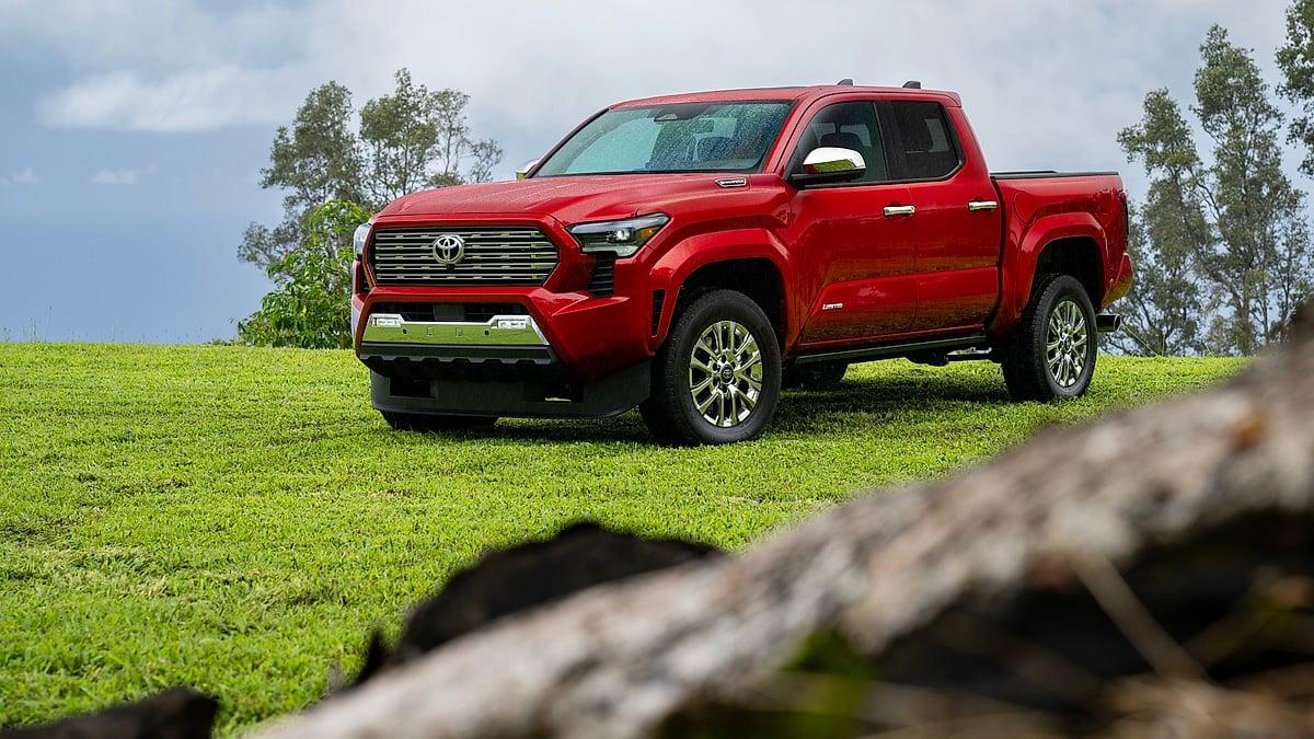 Red Toyota Tacoma parked on grassy hill outdoors
