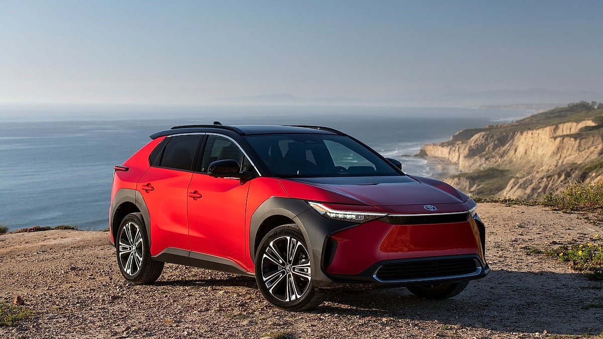 Red Toyota bZ4X electric SUV parked on a coastal cliff overlooking the ocean