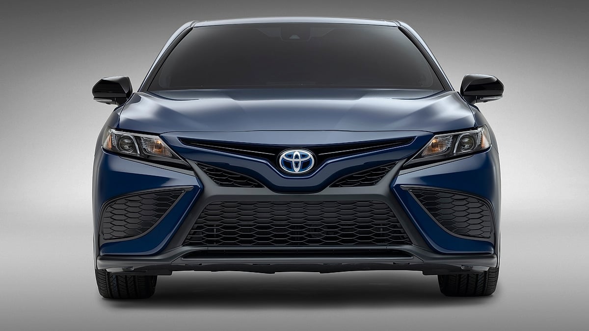 Blue Toyota Camry shown from the front in a studio setting with a close view of the grille and headlights.