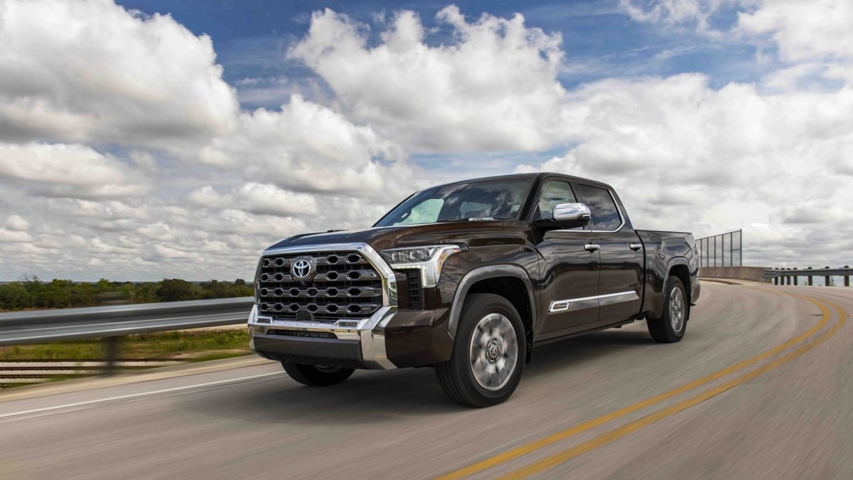 Dark brown Toyota Tundra 1794 Edition pickup truck driving on a highway bridge, front three-quarter view