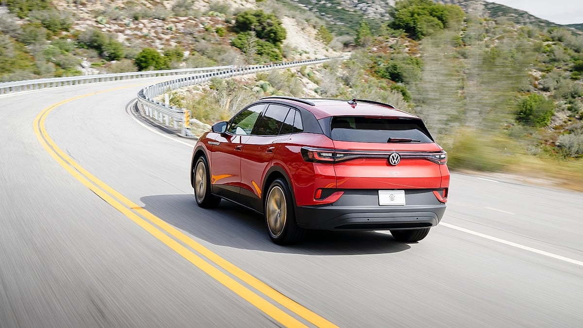 Rear view of a red Volkswagen ID.4 driving on a curving mountain road.
