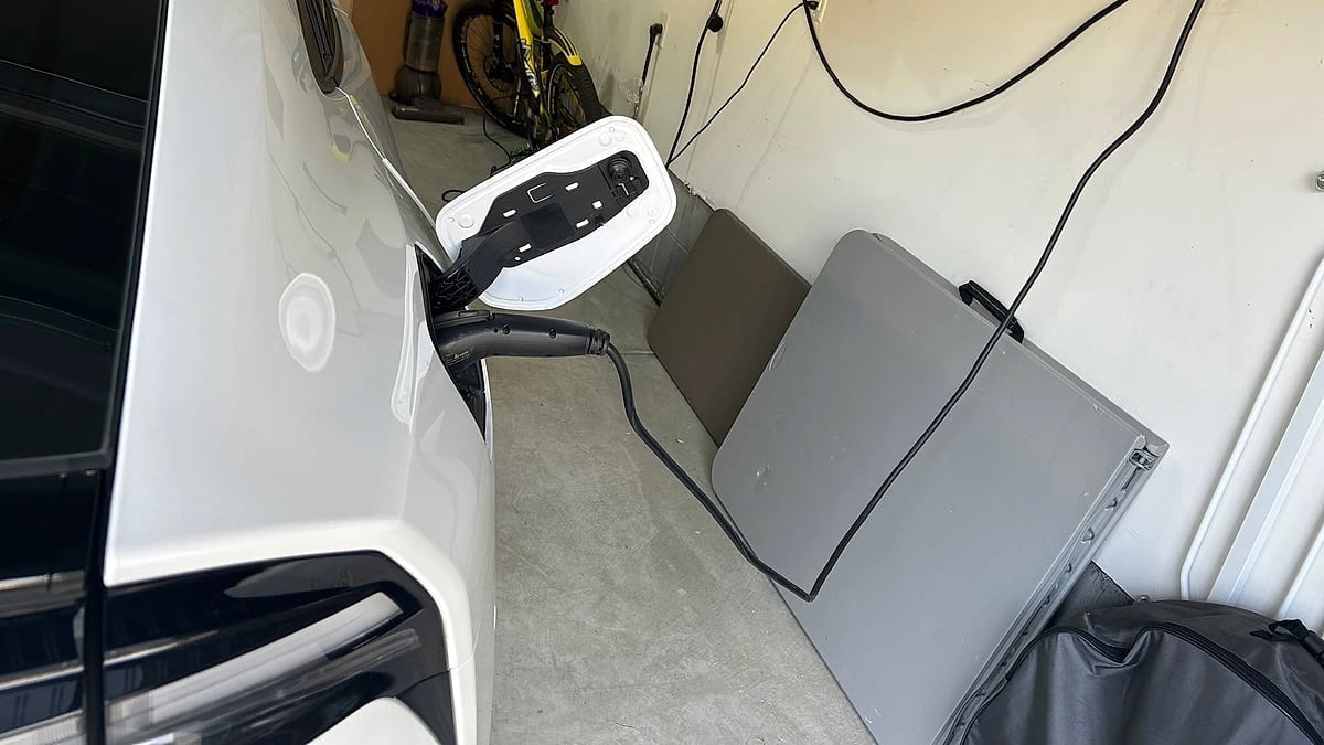 White plug-in vehicle charging inside a home garage with the charge port open.