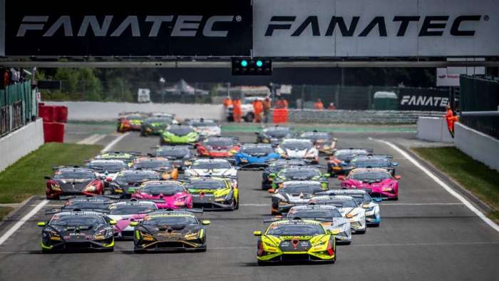 Image showing a field of brightly-colored Lamborghini Huracan Super Trofeo cars bunched together on the straight at the start of a race. 