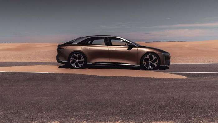 Image of a Eureka Gold Lucid Air parked on a sand-covered desert road.
