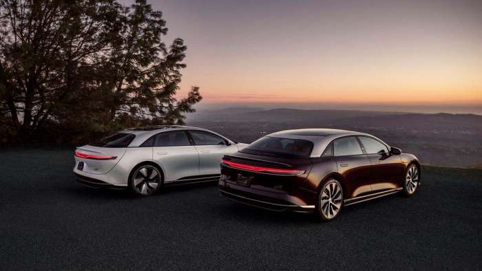 A Lucid Air Grand Touring and Grand Touring Performance are pictured parked on a hilltop at sunset.