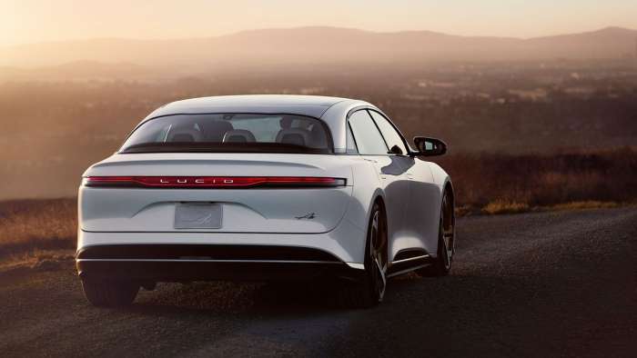 A white Lucid Air is pictured from the rear parked on a hilltop.