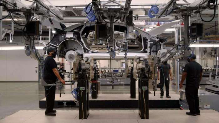 Image showing the battery installation area of the Lucid Air production line with workers positioned around the vehicle.