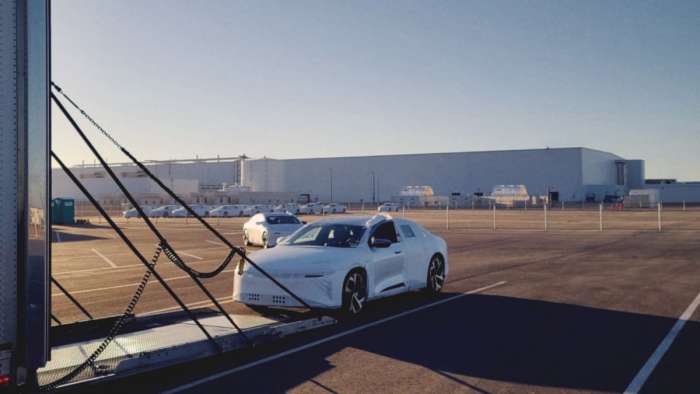 Image showing a Lucid Air covered in white protective wrapping being loaded into an enclosed trailer for shipping outside the company's Casa Grande, Arizona production facility.