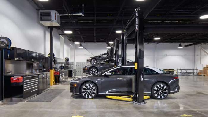 A trio of Lucid Airs are pictured in Lucid's new Montreal Service Centre. The closest car sits on the ground while the middle and furthest are raised on maintenance lifts.. 
