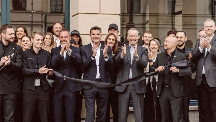 VIPs including CEO Peter Rawlinson are pictured smiling and clapping at the ribbon-cutting ceremony for Lucid's first European Studio in Munich.