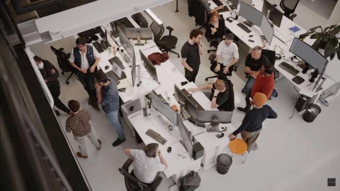 Lucid employees are pictured gathered around desks talking.