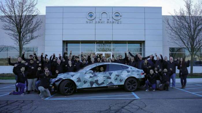 The record-breaking Tesla Model S is pictured outside ONE's headquarters along with staff members.