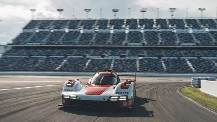 Front view of the Porsche 963 on the infield track with the Daytona Speedway grandstand in the background.