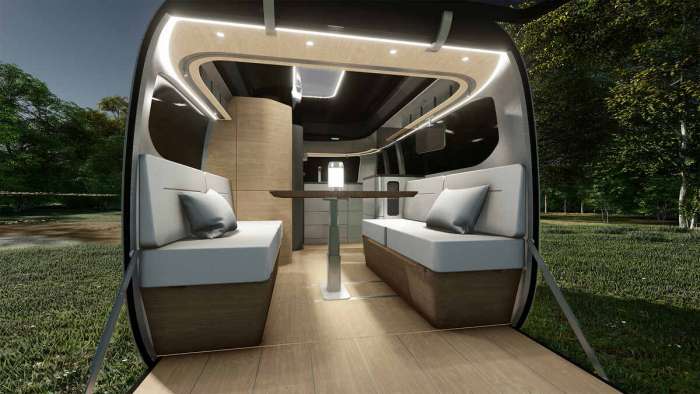 Interior shot of the Porsche Airstream trailer in dining mode with two sofa seats and a table between them.