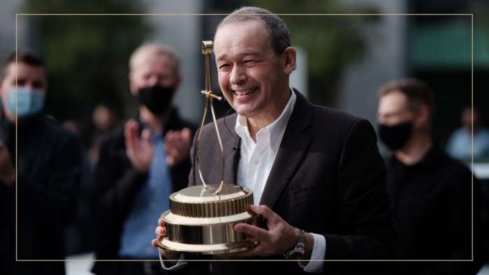 Image showing Lucid CEO Peter Rawlinson smiling and holding the MotorTrend Car of the Year trophy, which the Lucid Air won for 2021.