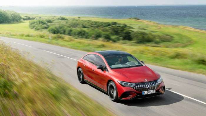 Image showing a red Mercedes AMG EQE driving on a country road.