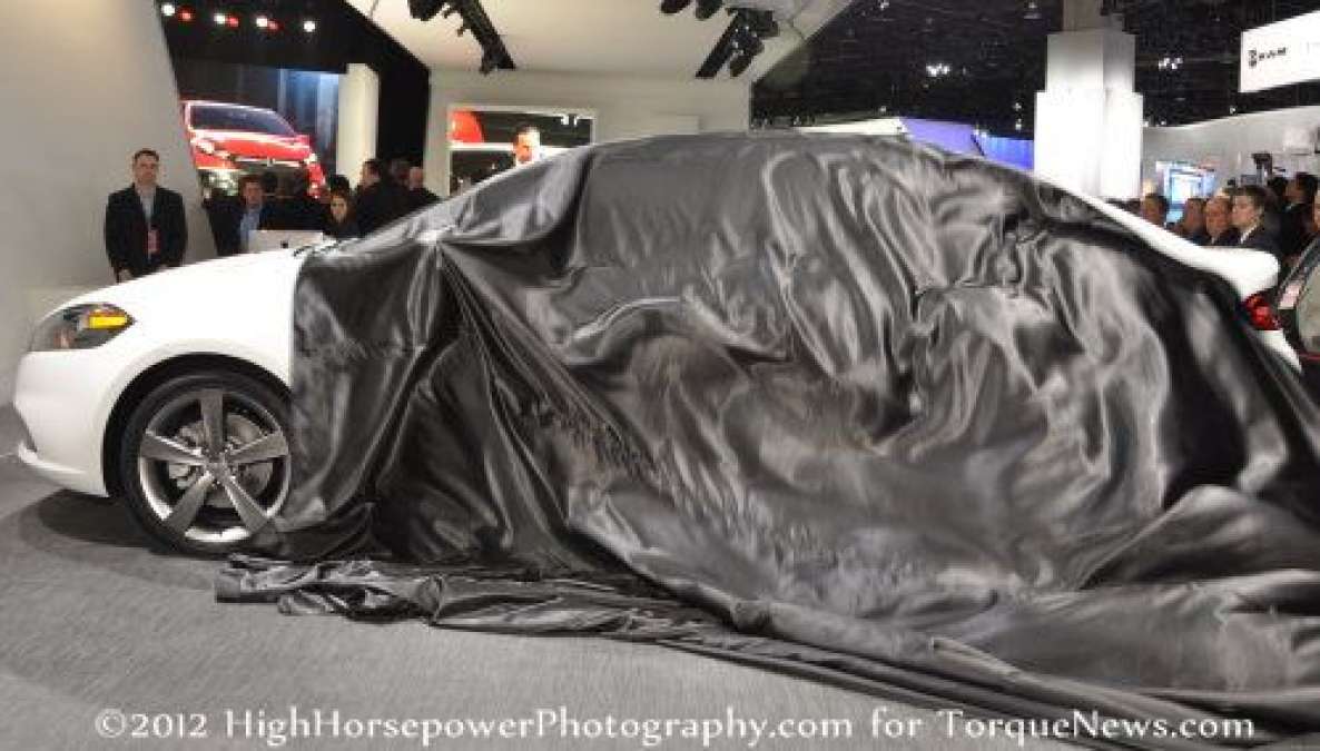 The cover being pulled off of the 2013 Dodge Dart