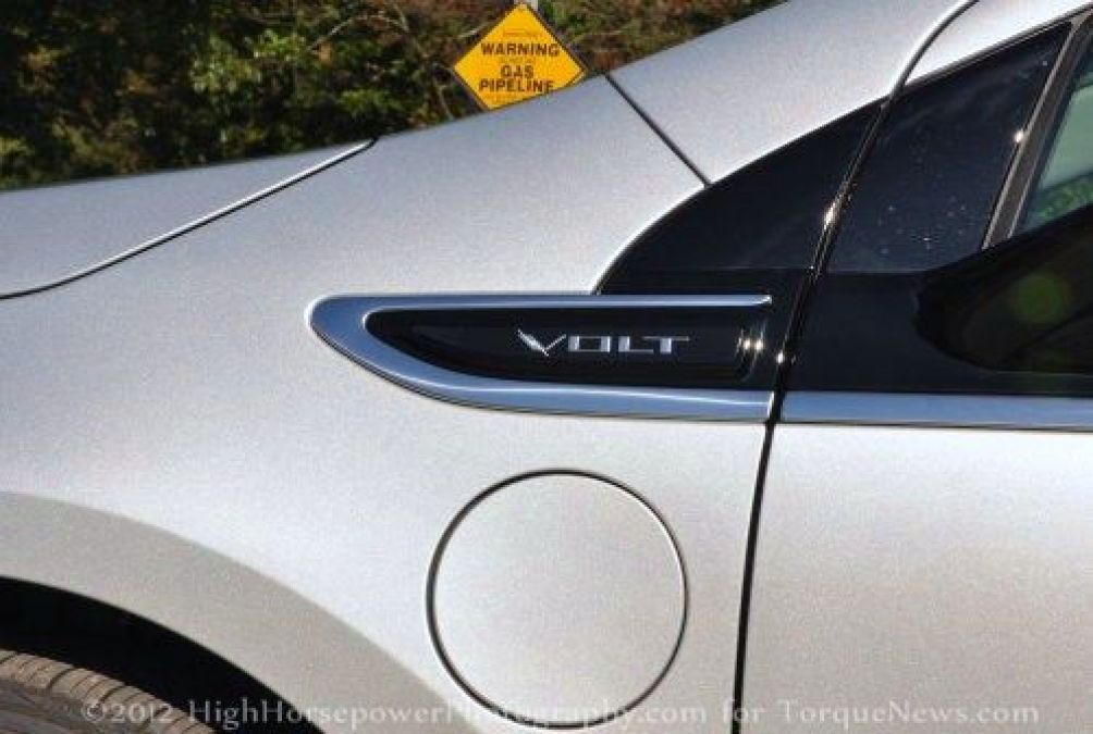 The Chevy Volt charging door and logo with a gas line sign in the background