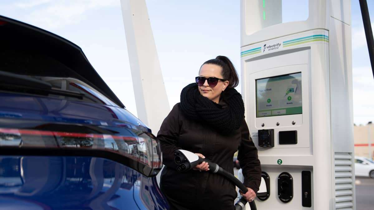 Image of EV owner charging in cold wearer courtesy of Electrify America