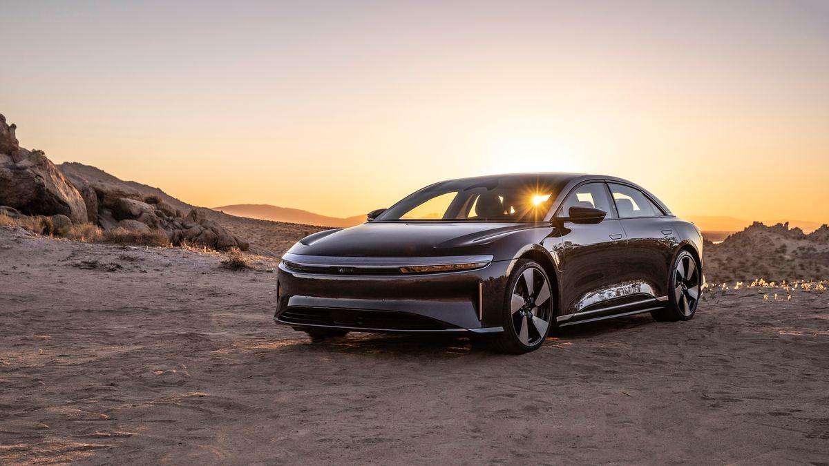 Image of a Zenith Red Lucid Air GT Performance parked in the desert. The setting sun is seen behind the car, shining through its windows.