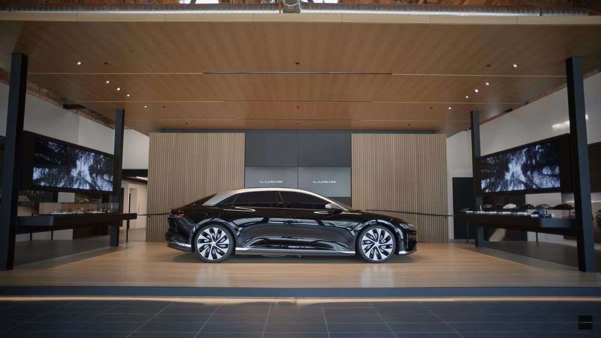 Image showing a dark red Lucid Air parked in the company's flagship Beverly Hills Studio. The dark red of the car contrasts with the light wood around it in the Studio.