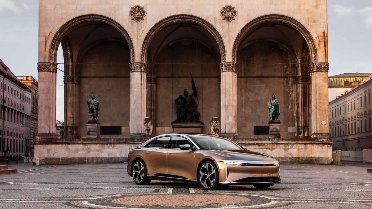 Image of a gold Lucid Air Dream Edition parked outside a historic building.