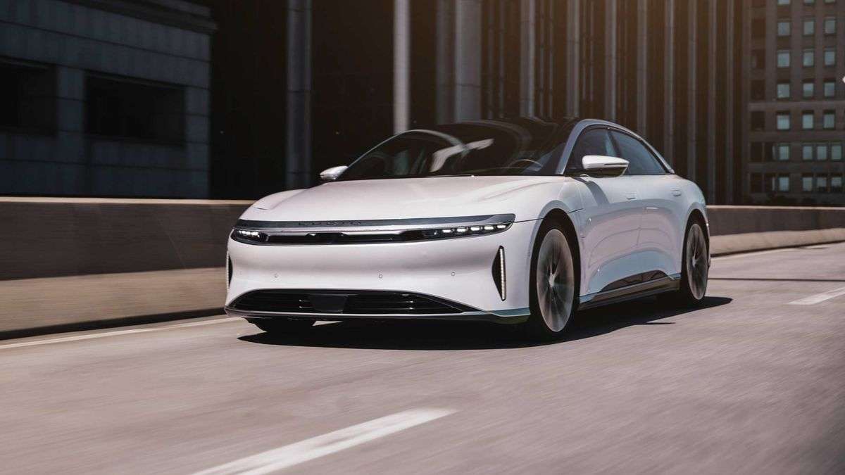 Image showing a white Lucid Air driving on an elevated highway through a city.