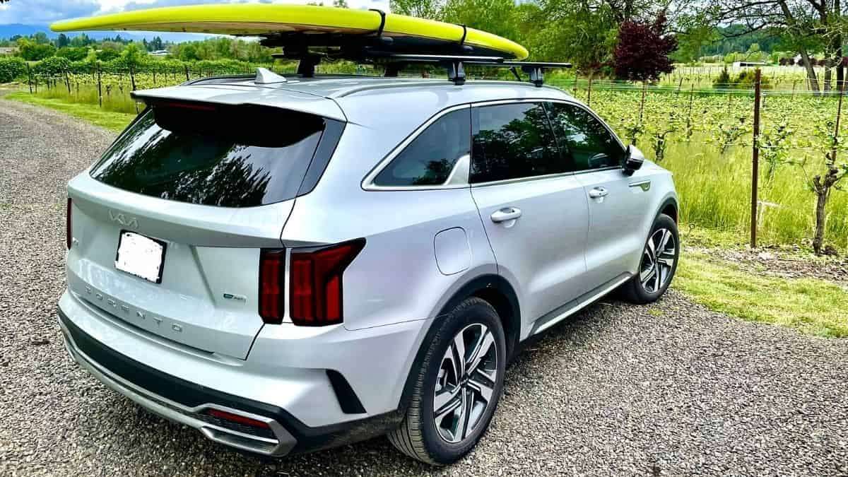 Silver Kia Sorento in front of vineyards with SUP board on roof