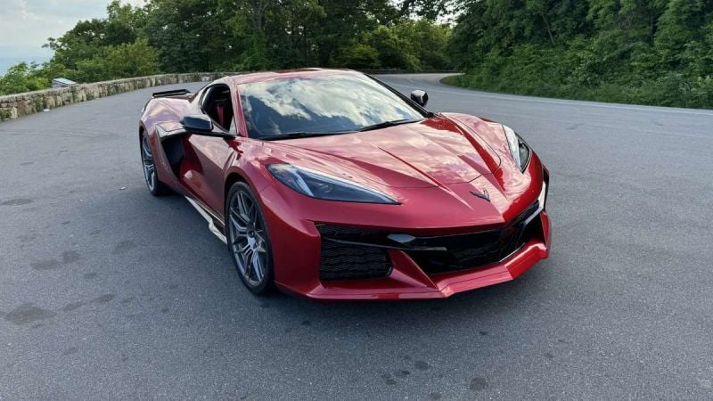 Red Chevrolet Corvette C8 parked on a scenic mountain road, front three-quarter view highlighting aggressive styling, low stance, and mid-engine sports car design.