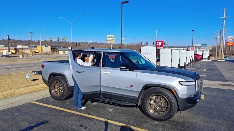 Gray 2023 Rivian R1T electric pickup shown from front three-quarter angle at a charging station.