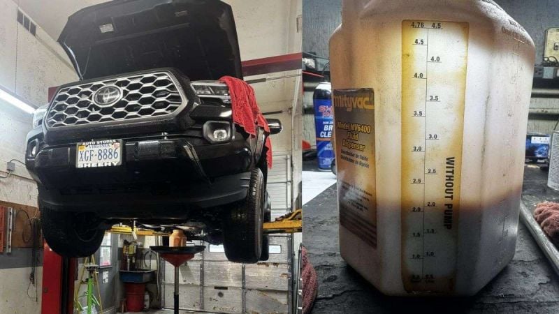 A 2023 Toyota Tacoma is elevated in a garage, with an oil catch pan below, alongside a fluid dispenser marked with measurements.