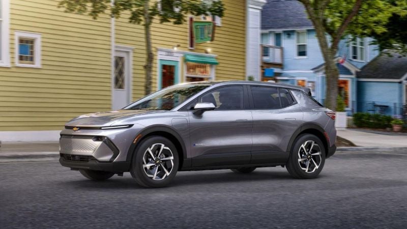 Silver SUV parked on a street with colorful buildings and trees in the background.