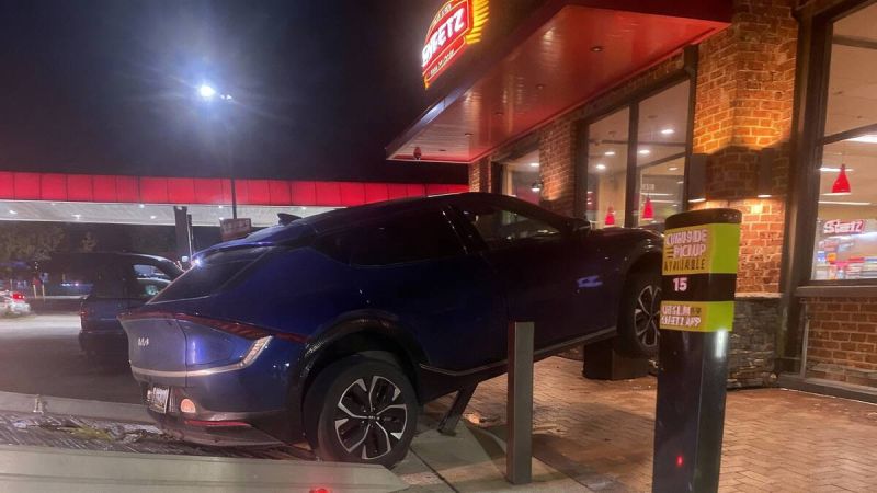 Car partially lifted onto a curbside pickup area, with a tow truck ramp nearby.