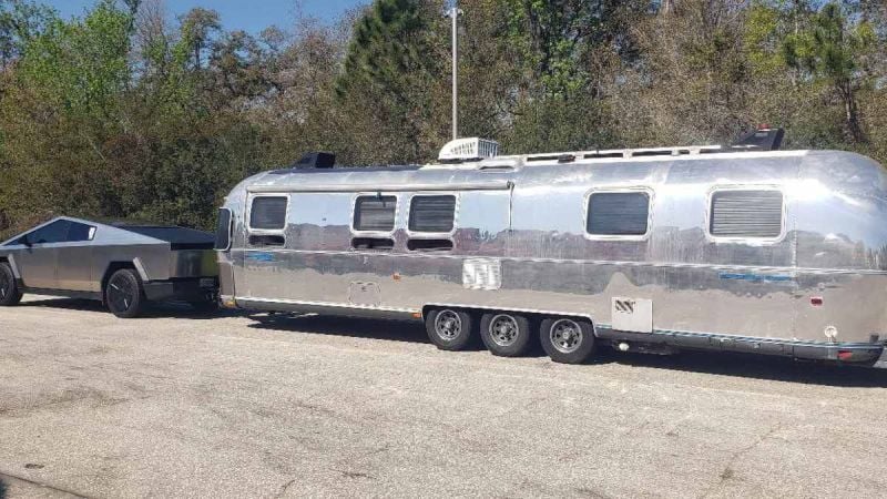 2024 Tesla Cybertruck towing a polished Airstream travel trailer, demonstrating electric truck towing capability and long-distance road travel