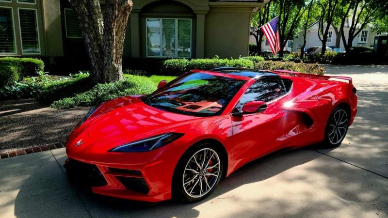 Red 2024 Chevrolet Corvette C8 parked in a residential driveway, showcasing mid-engine sports car design and exterior styling.
