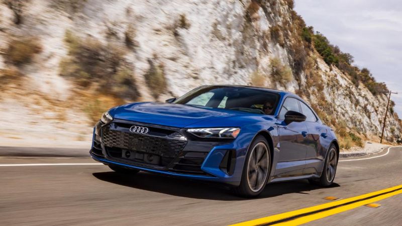 Blue Audi e-tron GT driving on mountain road with white limestone cliffs behind