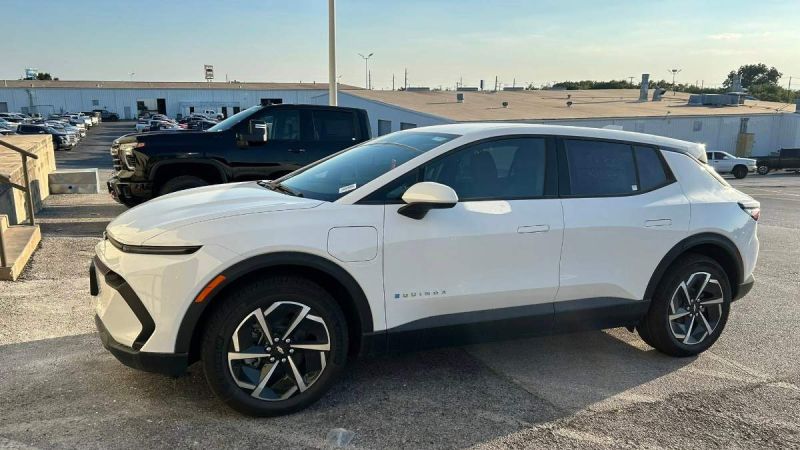White SUV parked in a lot, with a black truck in the background.