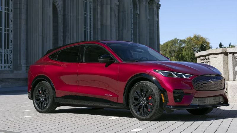Candy apple red Ford Mustang Mach-E electric SUV parked on stone pavement near neoclassical architecture