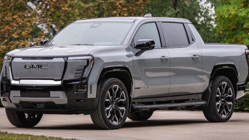 A silver 2025 GMC Sierra Denali pickup truck is shown featuring distinctive shaped LED lighting and black accents against a natural outdoor background.