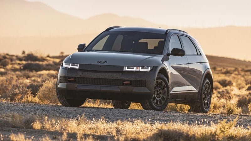 A 2025 Hyundai Ioniq 5 SUV parked on rugged terrain, with golden sunlight illuminating the background mountain range.