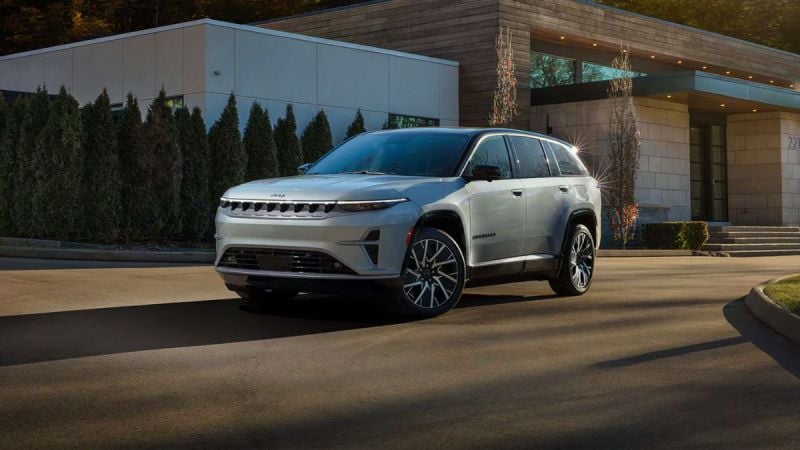 2025 Jeep Wagoneer S EV in pearl white, parked at modern architectural building with landscaped trees