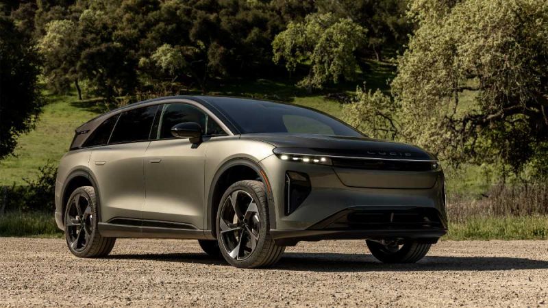 Lucid Gravity electric SUV parked on gravel with lush green forest background